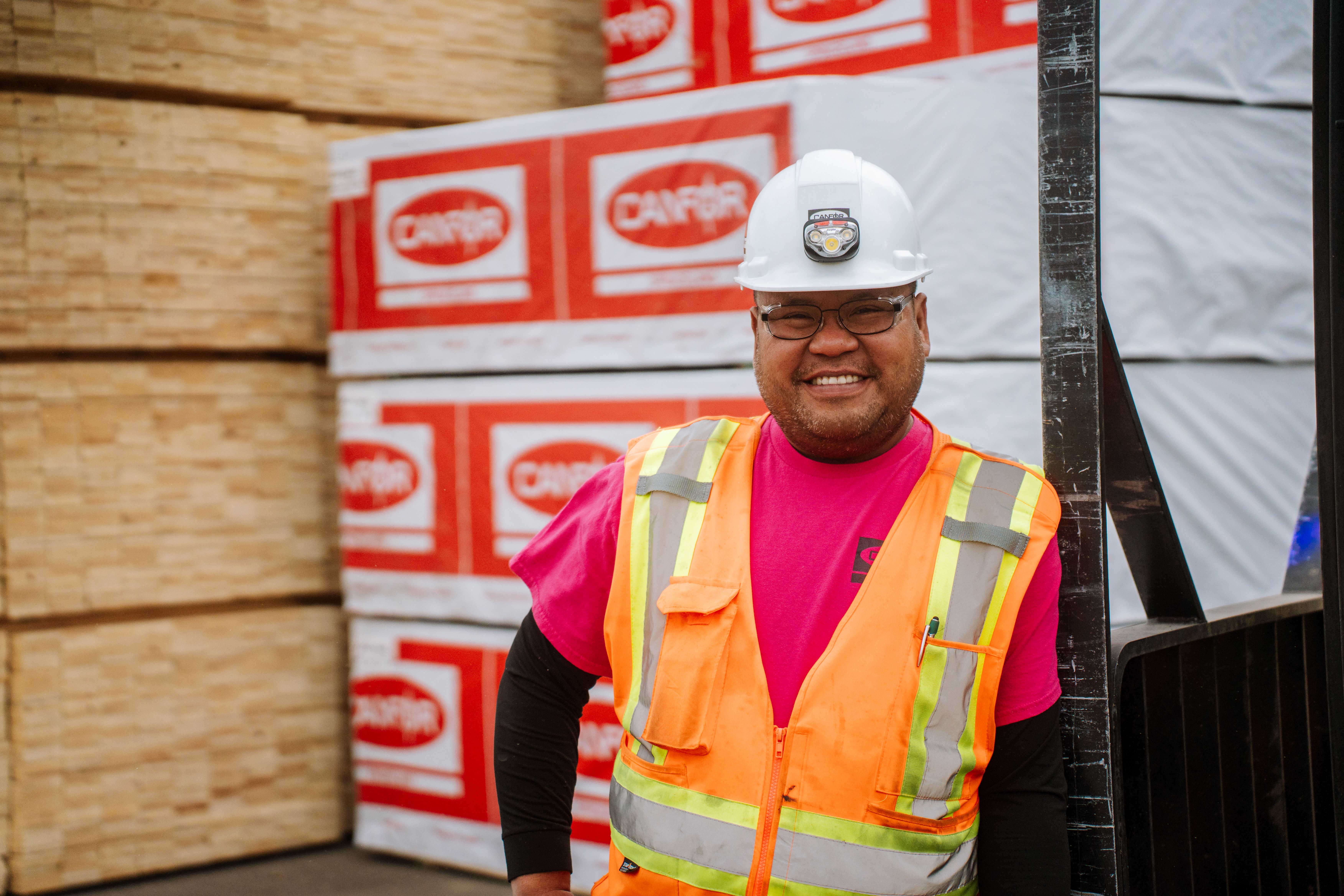 Worker at a BC forestry operation with stacked lumber